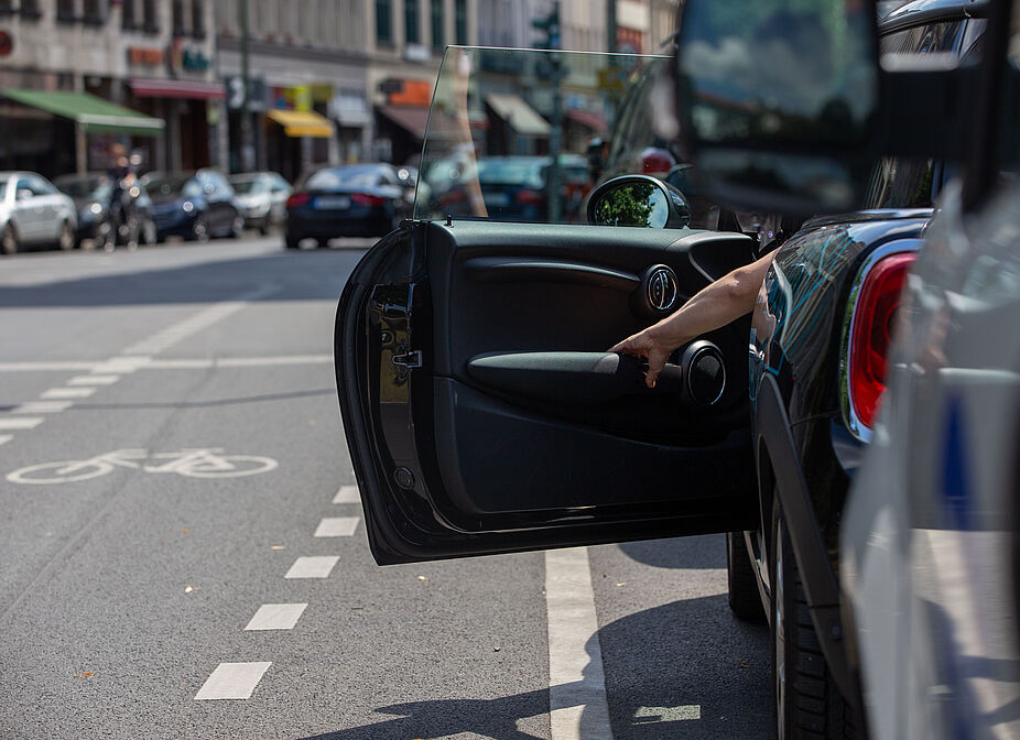 Dooring - eine Gefahr für Radfahrende Plötzlich geöffnete Autotür im Straßenverkehr – typische Gefahrensituation für vorbeifahrende Radfahrende.
